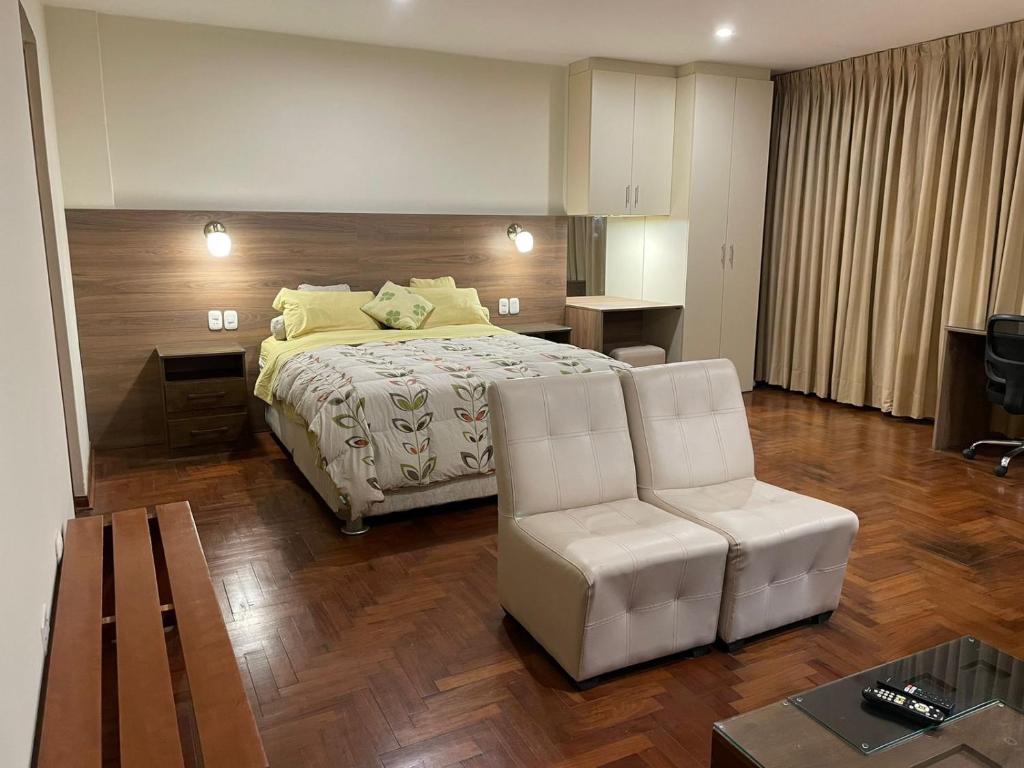 利马FLAT AMOBLADO EN PUEBLO LIBRE - LIMA - PERÚ的一间卧室配有一张床、一把椅子和一张桌子