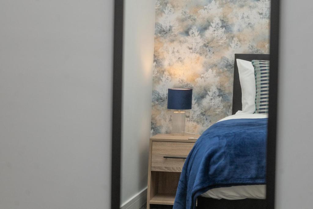 邓布兰Historical Holmehill Lodge的一间卧室配有蓝色的床和带灯的床头柜
