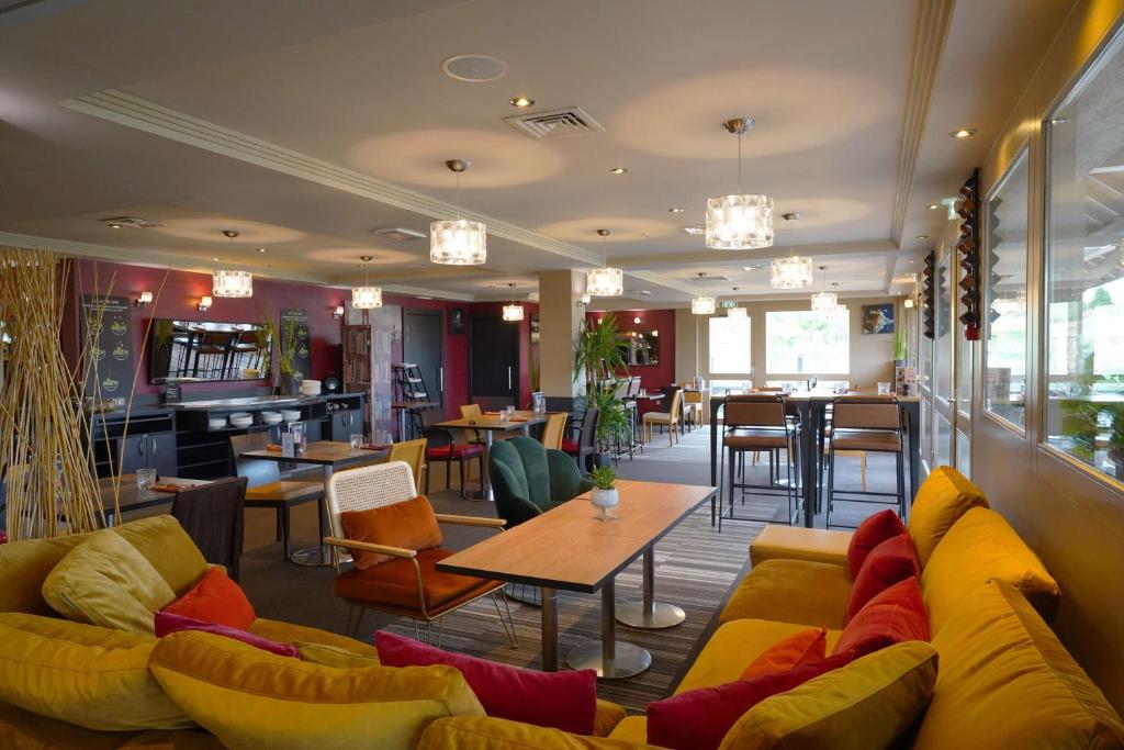 莫伯日车间117贝斯特韦斯特酒店的餐厅设有黄色的沙发和桌椅