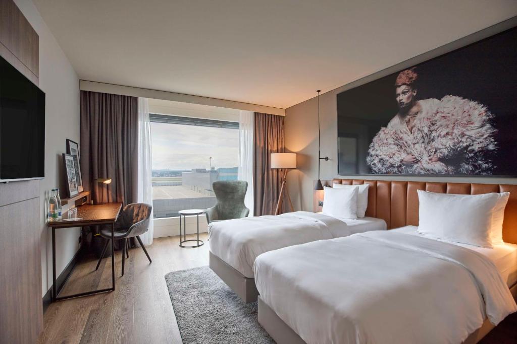 克洛滕Radisson Blu Hotel Zurich Airport的酒店客房设有两张床、一张书桌和一个窗户。