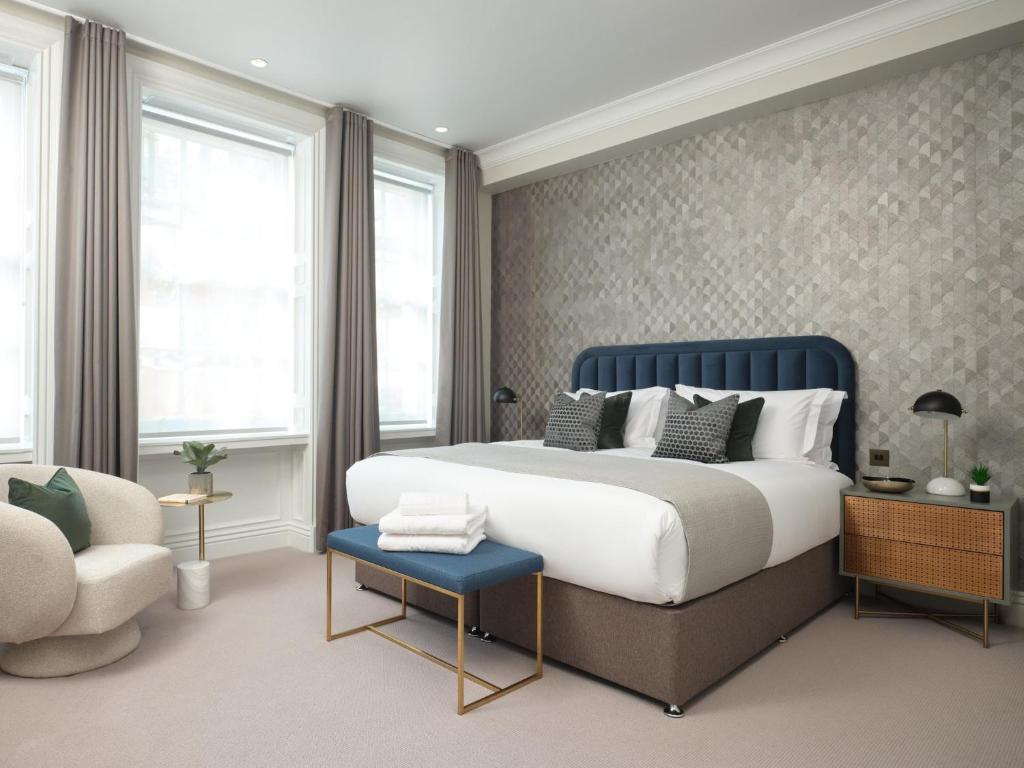 伦敦Deluxe Mayfair Luxury Apartment的一间卧室配有一张特大号床和一把椅子