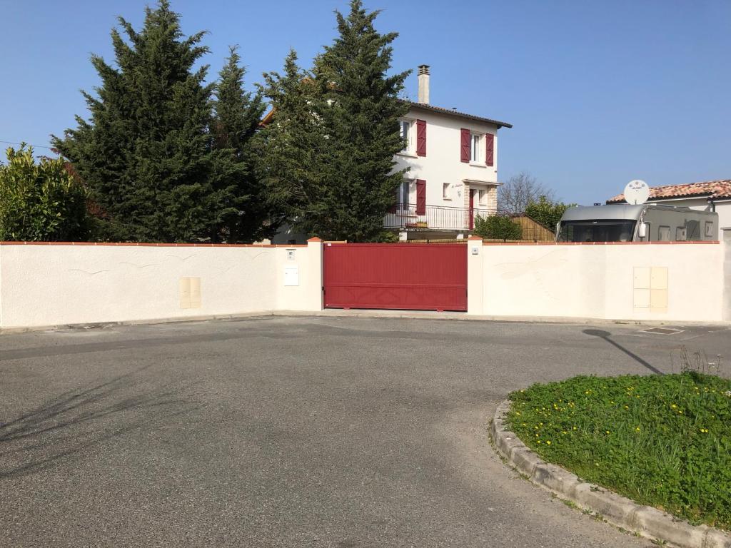 图卢兹Villa La Libellule Grand Jardin et Parking Privé的车道,在房子前面有红色门