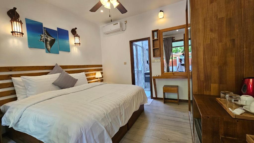 迪古拉Dhonfalhu Dhigurah的卧室设有一张白色大床和一扇窗户。