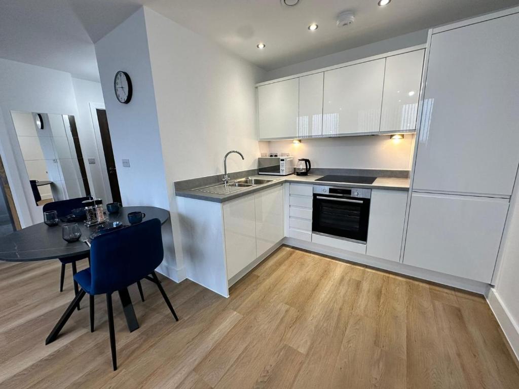 曼彻斯特1 Bed Apartment near Old Trafford with free car park的厨房配有白色橱柜、桌子和柜台。