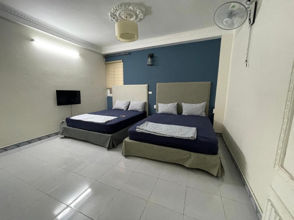 河内Sword lake hostel的配有2张床的客房,拥有蓝色的墙壁和白色的地板