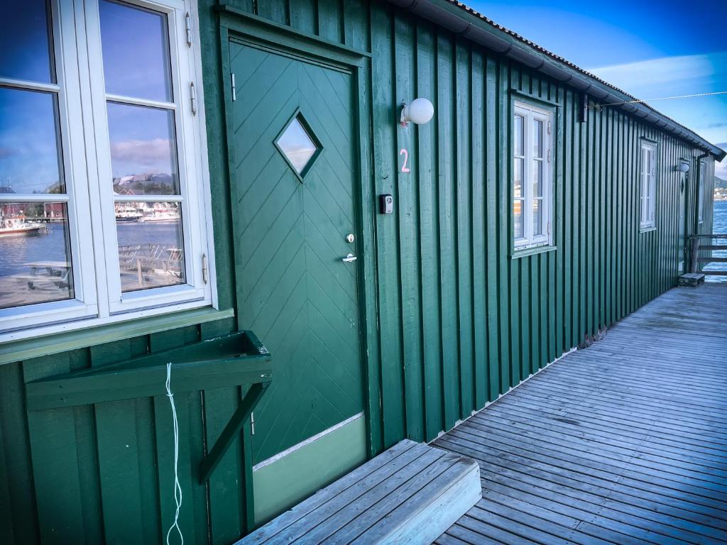 巴尔斯塔Kræmmervika Rorbuer - Rustic Cabins in Lofoten的绿色的建筑,设有门窗