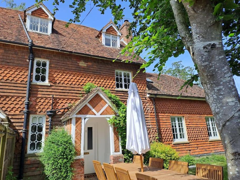 法纳姆Cottage 2, Northbrook Park, Farnham-up to 6 adults的一个带遮阳伞和桌椅的房子