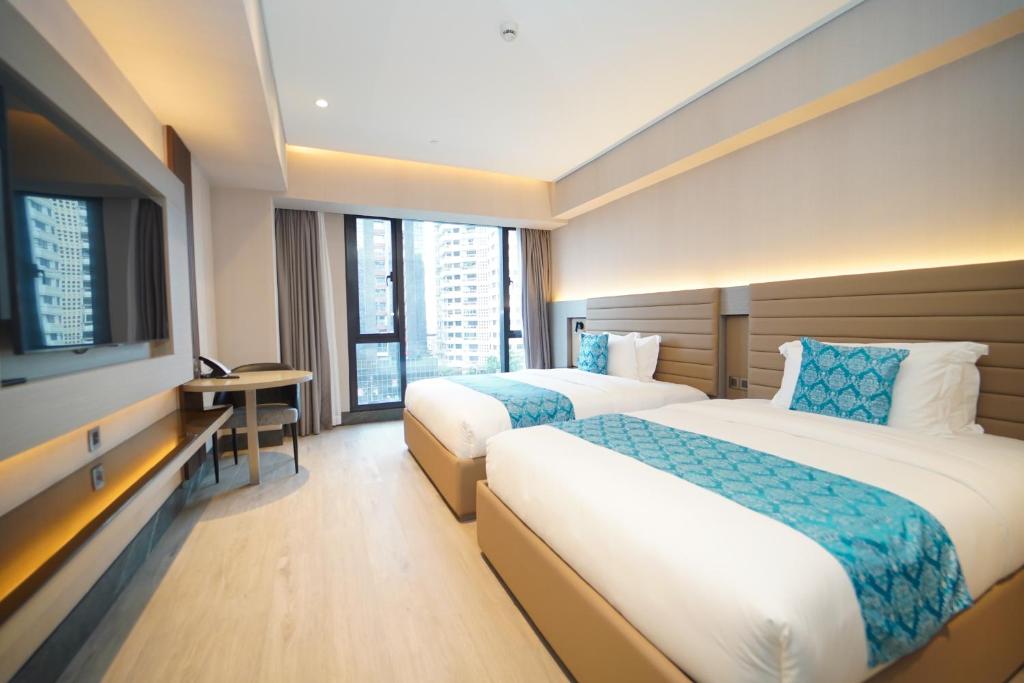 马尼拉Bayprime Hotel的酒店客房设有两张床和一台平面电视。