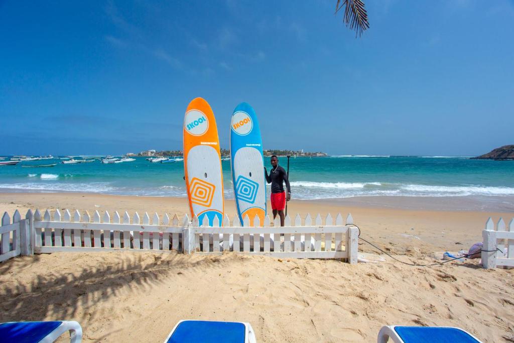 达喀尔拉马德拉戈 - 冲浪海滩碧海酒店的站在海滩冲浪板前的人