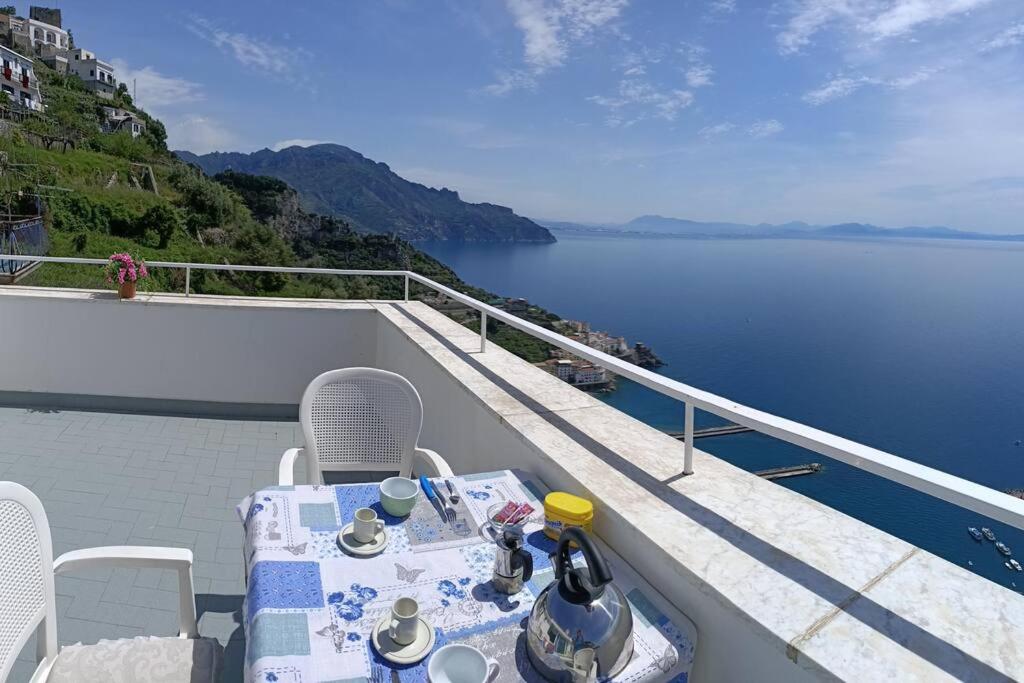 阿马尔菲Casa Vacanze La Rosa Del Mare的俯瞰水面的阳台配有桌椅