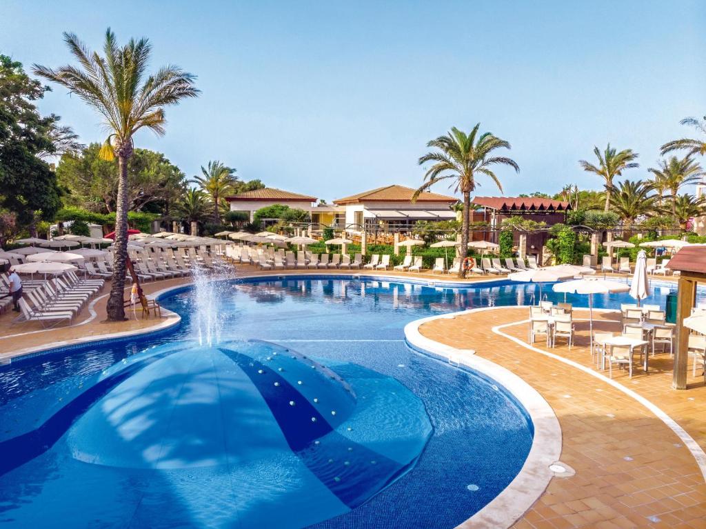 卡兰博希Zafiro Menorca的棕榈树和椅子的度假村的游泳池