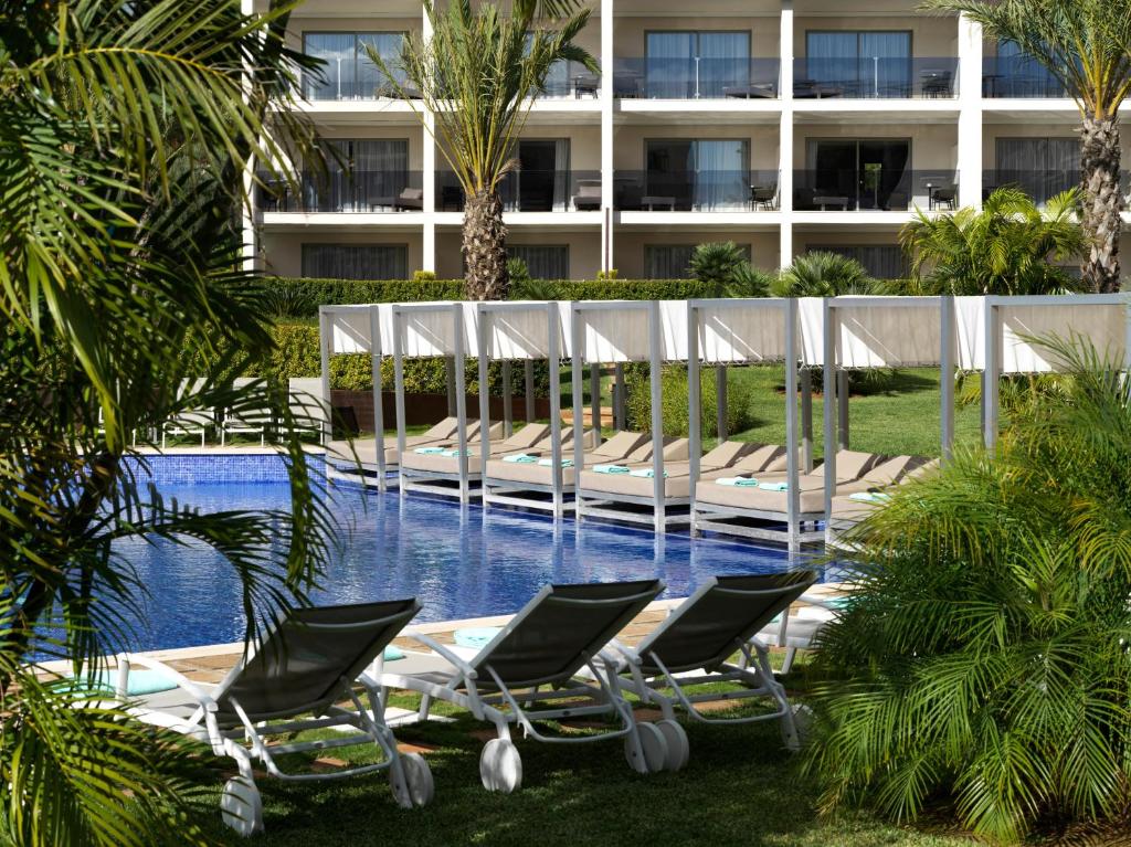 帕尔马诺瓦扎菲洛帕莱斯帕尔马诺瓦酒店的一组躺椅,位于游泳池旁