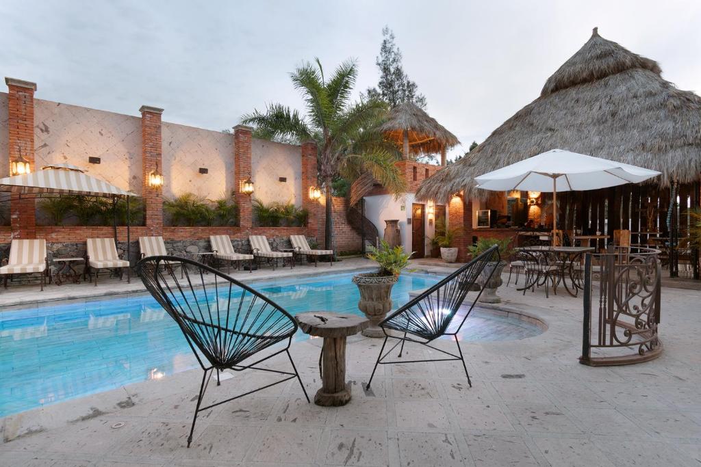 阿吉吉克Casa Miura Hotel Boutique的一个带椅子和遮阳伞的游泳池的度假酒店