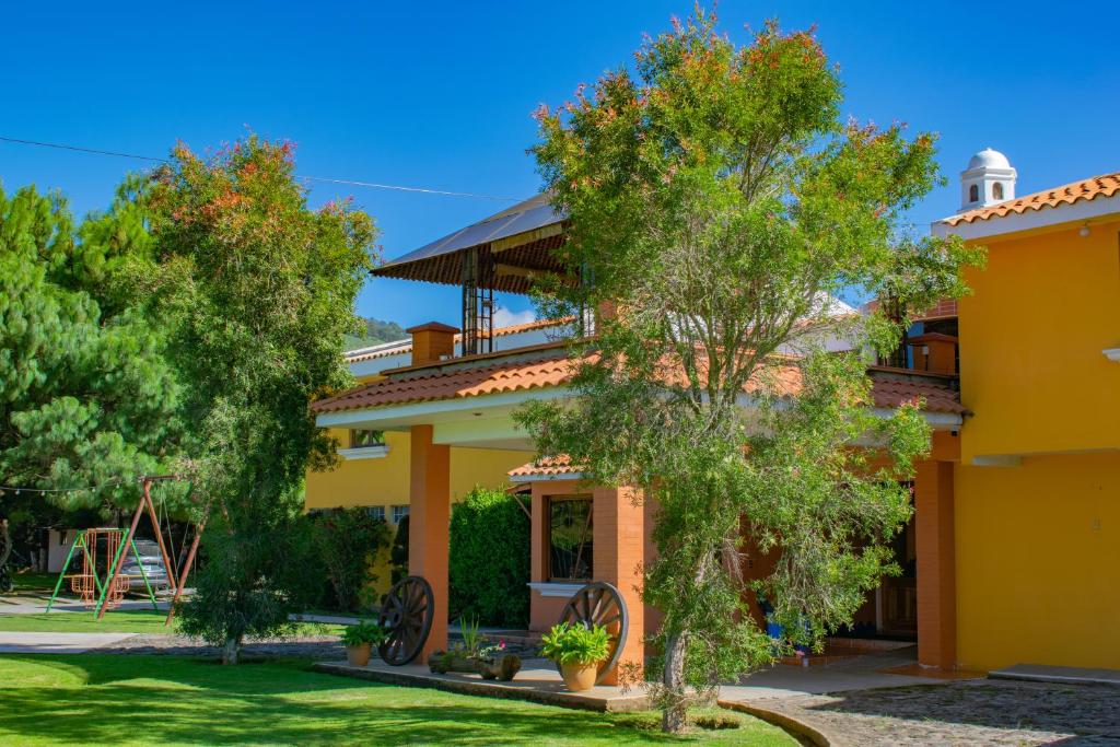 克萨尔特南戈Hacienda Grande Hotel的前面有树木的黄色房子