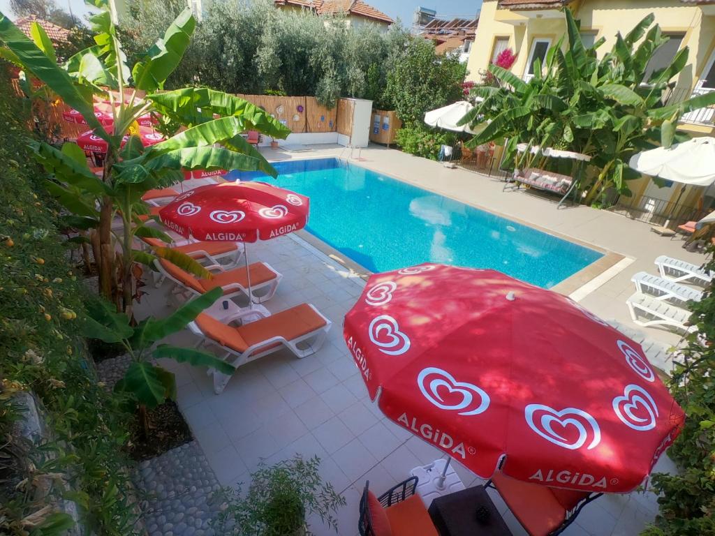 厄吕代尼兹Sarıhan Apart Otel的一个带两把红色遮阳伞和椅子的游泳池以及一个游泳池