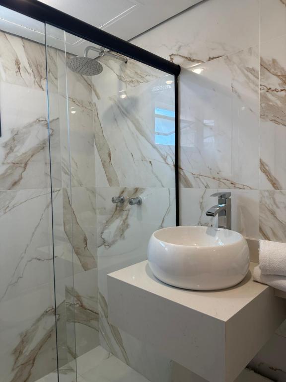 巴鲁埃里Hotel & Residência Alphaville的一间带水槽和玻璃淋浴的浴室
