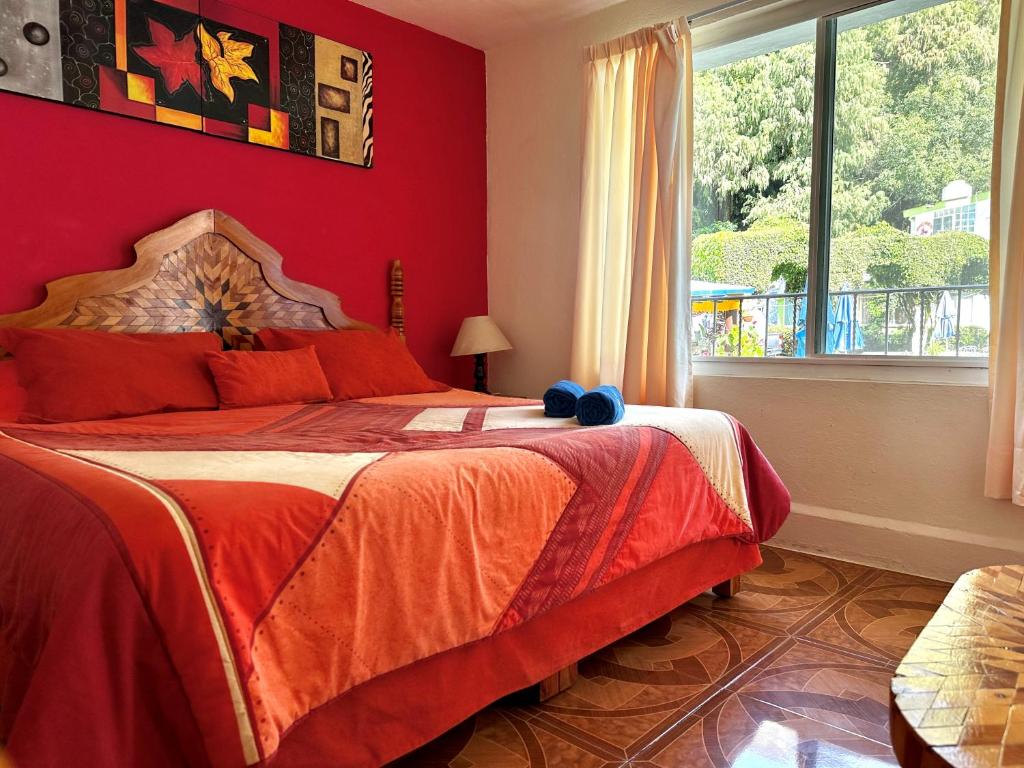 迪坡斯特兰BUNGALOWS ANDREA的一间卧室设有一张红色墙壁和窗户的床