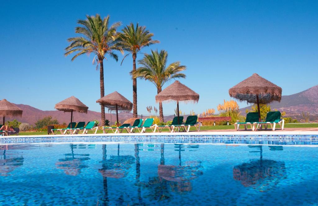 卡拉德米哈斯Beautiful luxurious 2 bedroom apartment with a breathtaking view at La Cala Golf的一个带椅子和遮阳伞的游泳池以及棕榈树