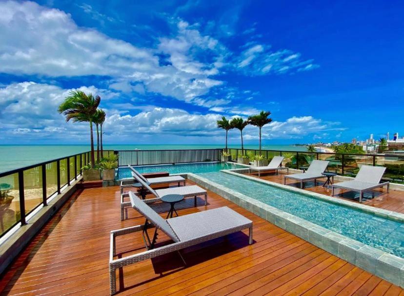 若昂佩索阿Arpoar Suítes Hotel Unidade 120的一个带椅子的甲板上的游泳池,享有海景