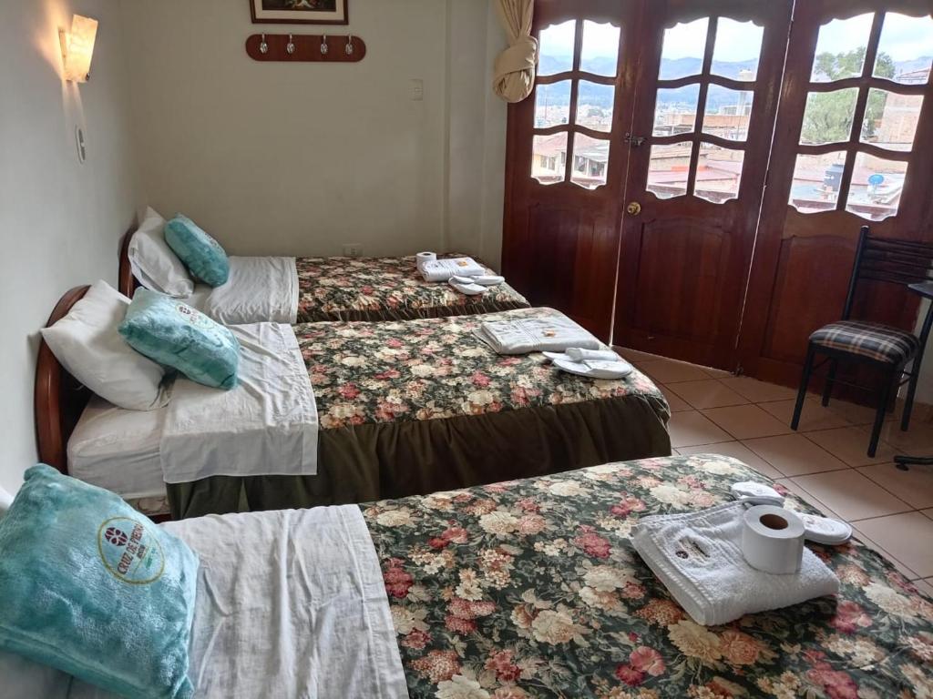 卡哈马卡Hostal Turismo Cruz de Piedra EIRL-Cajamarca的酒店客房设有三张床和一张桌子