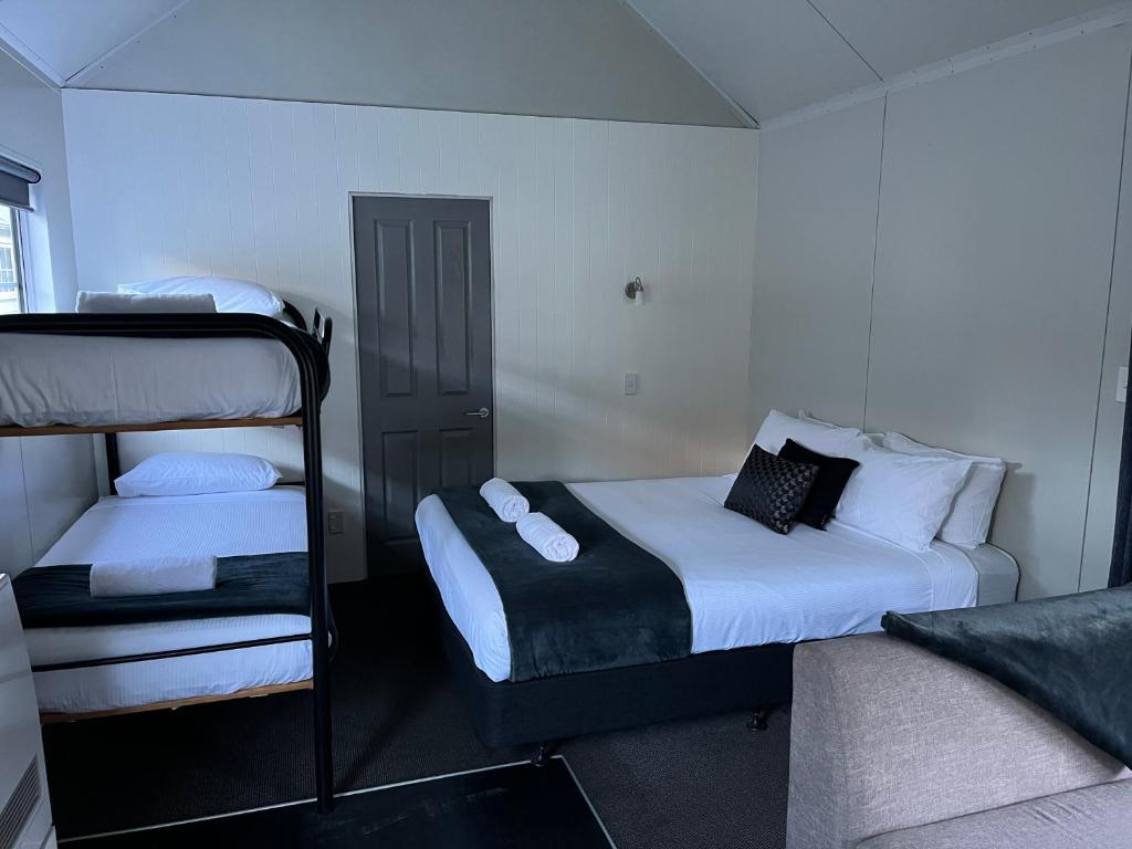 箭镇Hampshire Holiday Parks - Arrowtown的客房设有两张床和一张双层床。