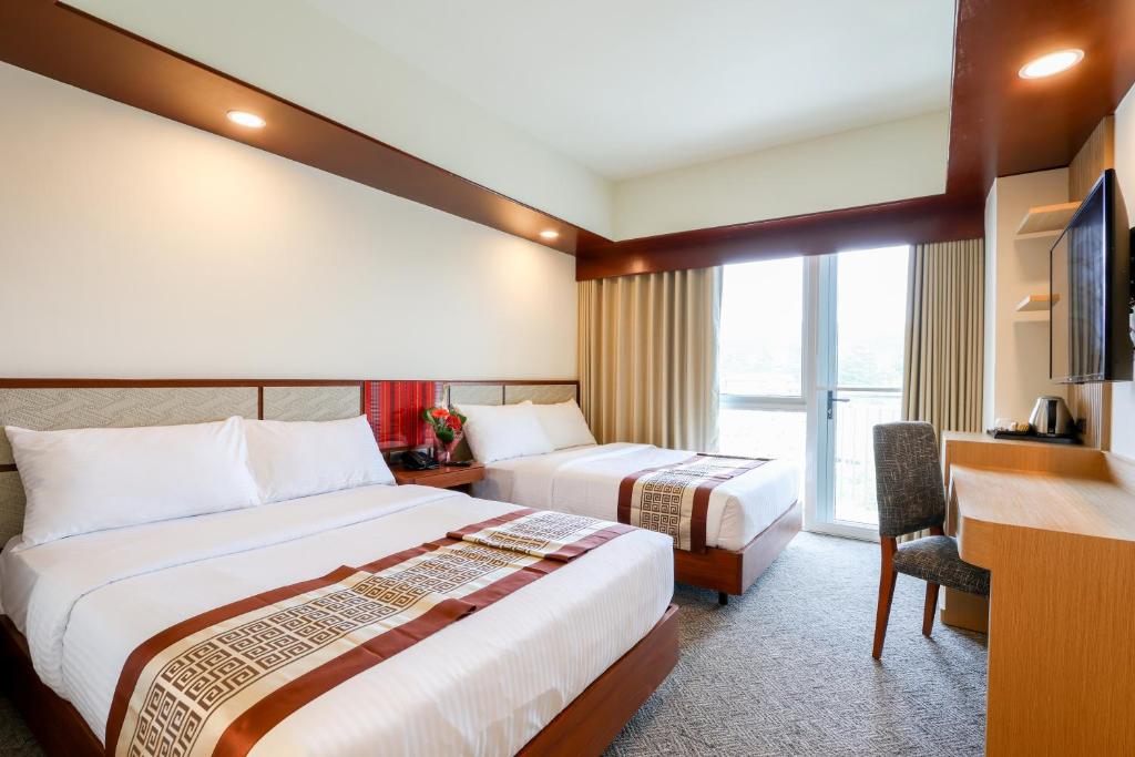 碧瑶Sotogrande Hotel Baguio的酒店客房配有两张床和一张书桌