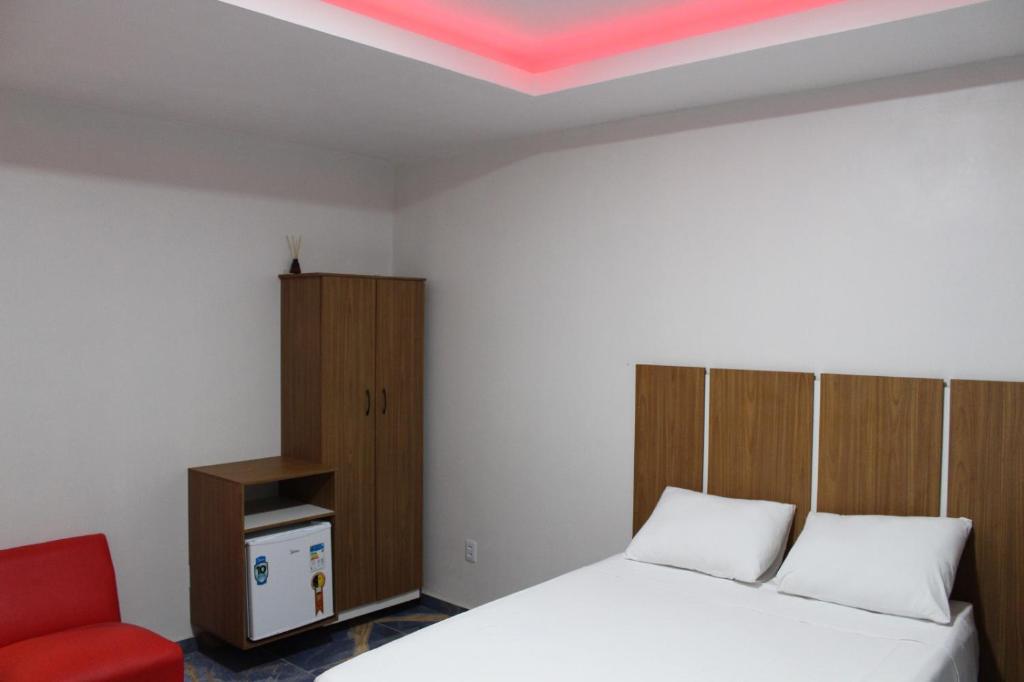 博阿维斯塔Boa vista, Hotel Jardim Tropical的一间卧室配有一张床和一张红色椅子