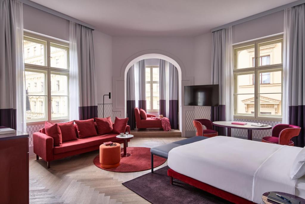 布拉格Falkensteiner Boutique Hotel Prague的客厅配有红色家具和床