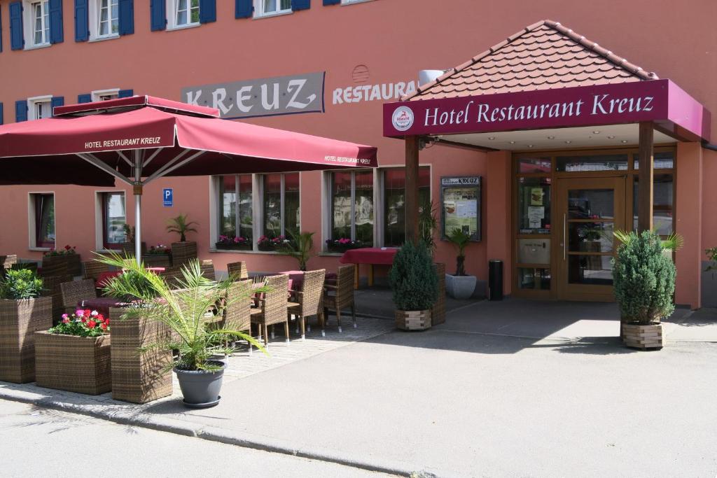SpaichingenHotel Restaurant Kreuz Spaichingen的大楼前的餐厅,配有桌子和遮阳伞