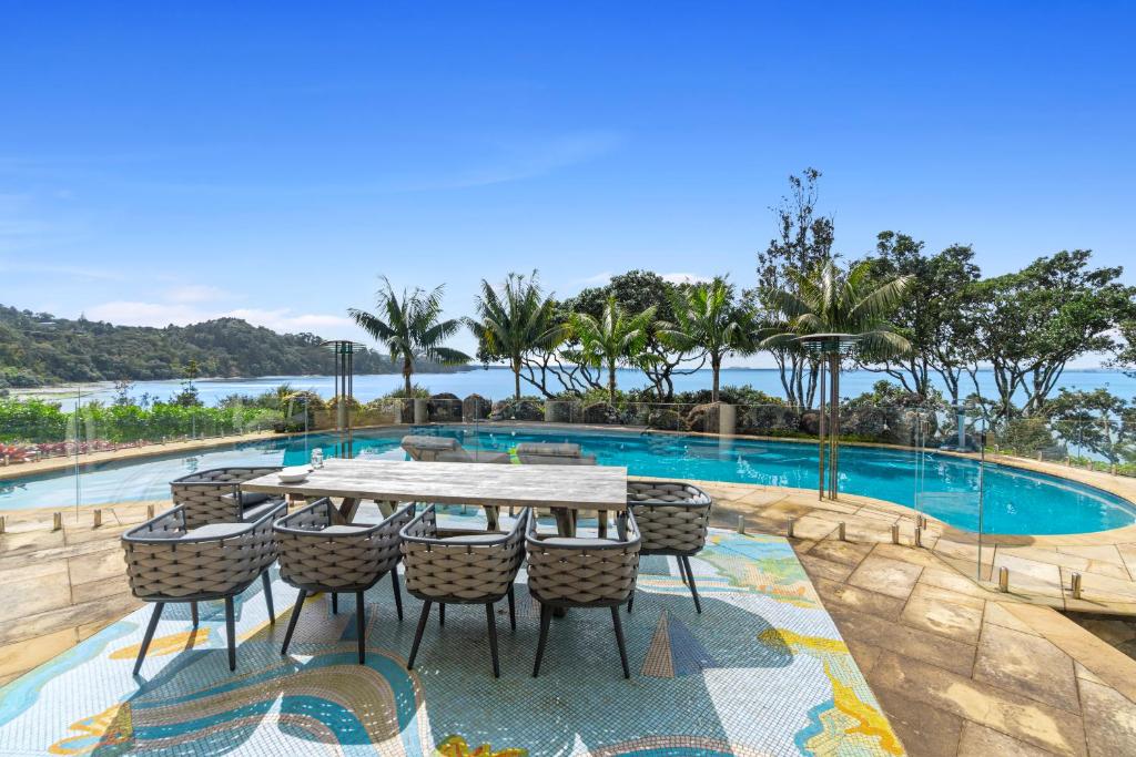 TitirangiBeachside Luxury - Laingholm Holiday Apartment的游泳池旁的桌椅