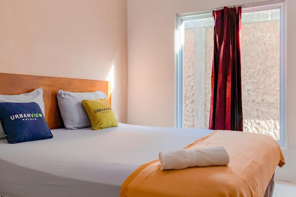 班贾尔马辛Urbanview Hotel AVA Banjarmasin by RedDoorz的卧室配有带枕头的大床和窗户。