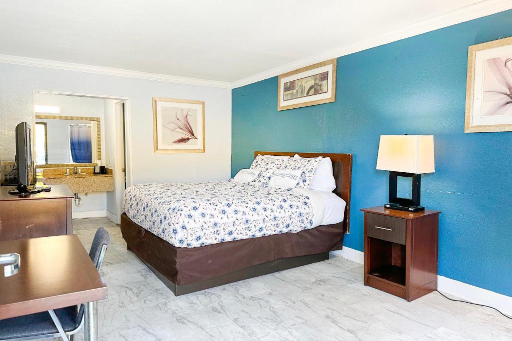 哈蒂斯堡Paradise Inn By OYO Hattiesburg North的一间卧室设有一张床和蓝色的墙壁