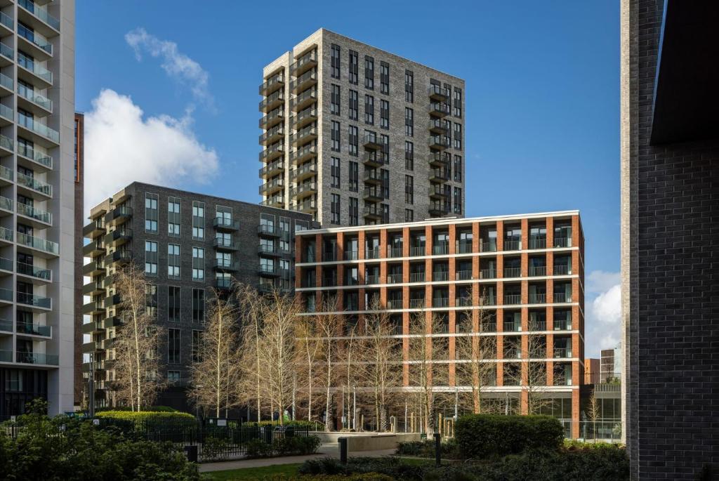 伦敦Botanical-inspired apartments at Repton Gardens right in the heart of Wembley Park的两座高大的建筑,前面有树木