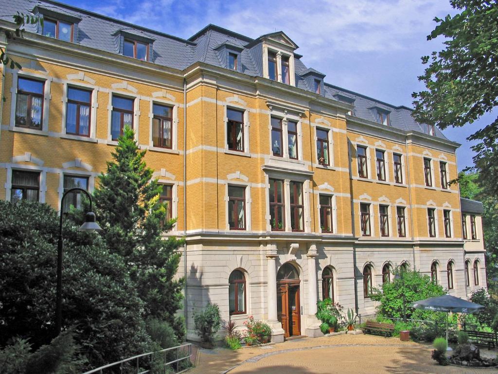 奥厄Sächsisches Gemeinschafts-Diakonissenhaus ZION e. V.的一座黄色的大建筑,前面有一棵树