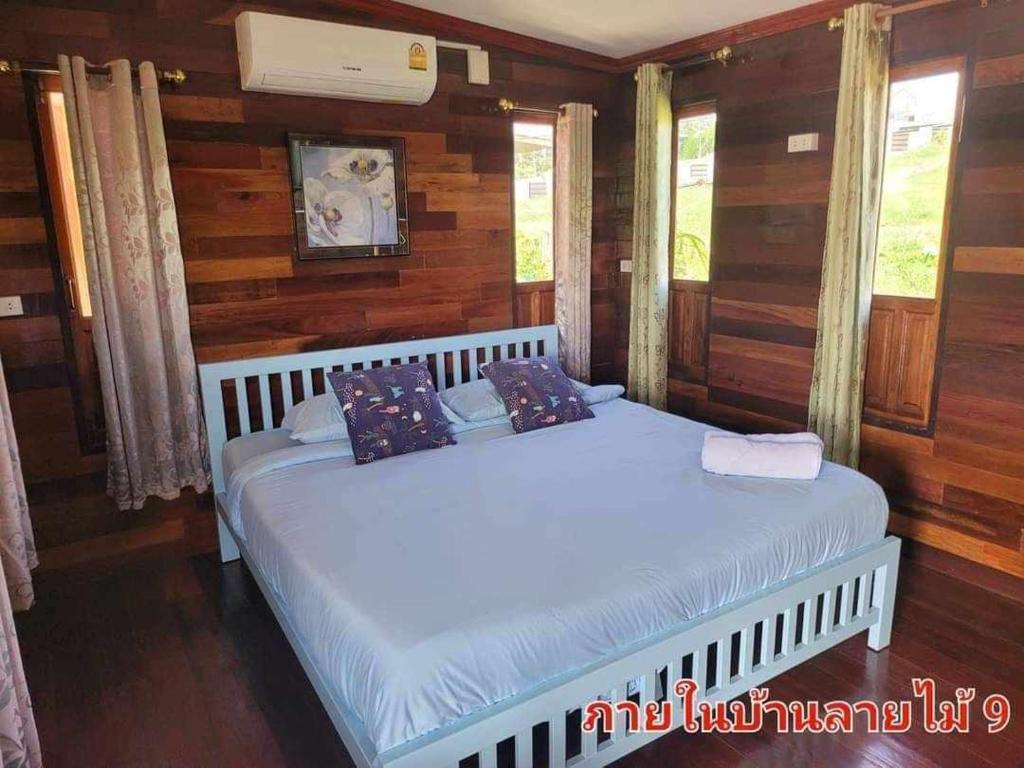 Ban Non Na YaoThe Memorize Resort的卧室设有两张床,配有木墙和窗户。
