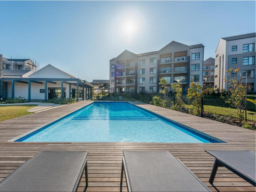 巴利托Ballito Village Luxury Apartments by DropInn的一座带长椅的游泳池,毗邻一些建筑