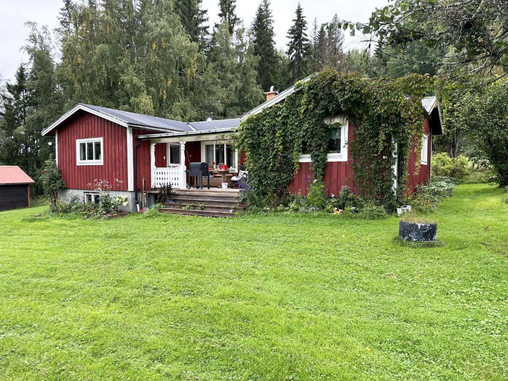 NåsWilderness cabin in Nas near the Vasterdal River的一座红房子,旁边长着常春藤