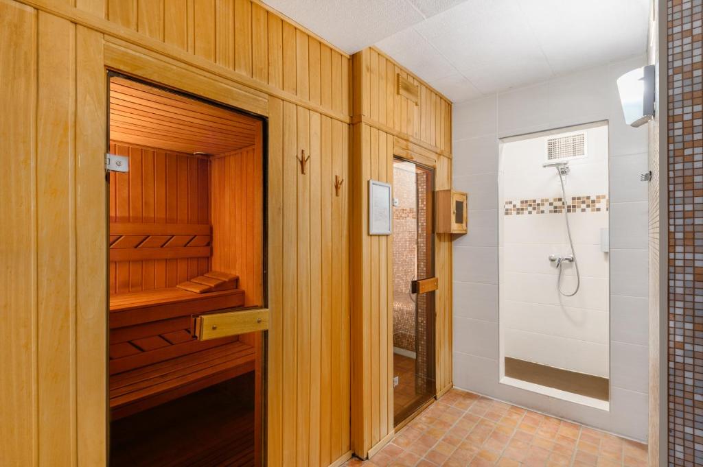 塞克希费黑瓦尔Castrum Hotel Székesfehérvár的带木制橱柜的浴室内的步入式淋浴间