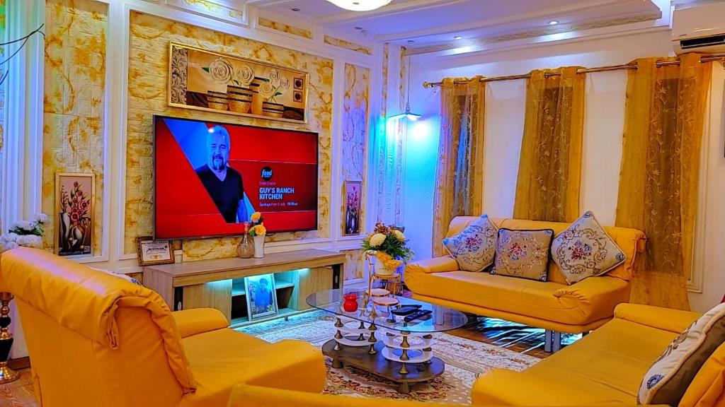 库马西Golden Aurora Lodge的客厅配有黄色家具和平面电视