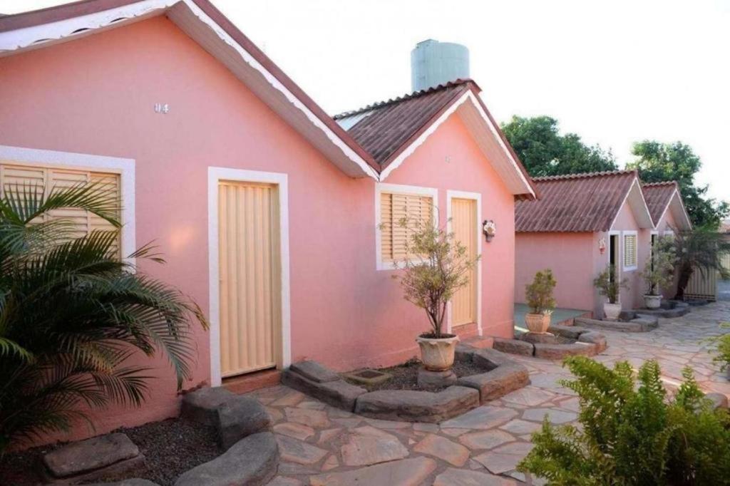 卡达斯诺瓦斯Pousada Caldas Novas的粉红色的房子,前面有植物