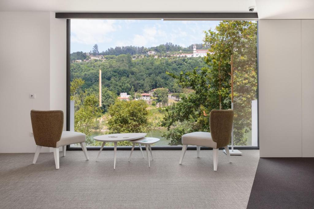 派瓦堡Douro Green的客房设有两把椅子、一张桌子和大窗户