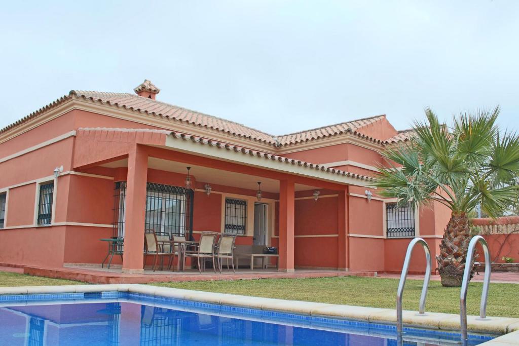 奇克拉纳－德拉弗龙特拉Chalet Carlos El Campito的一座红色的房子,前面有一个游泳池
