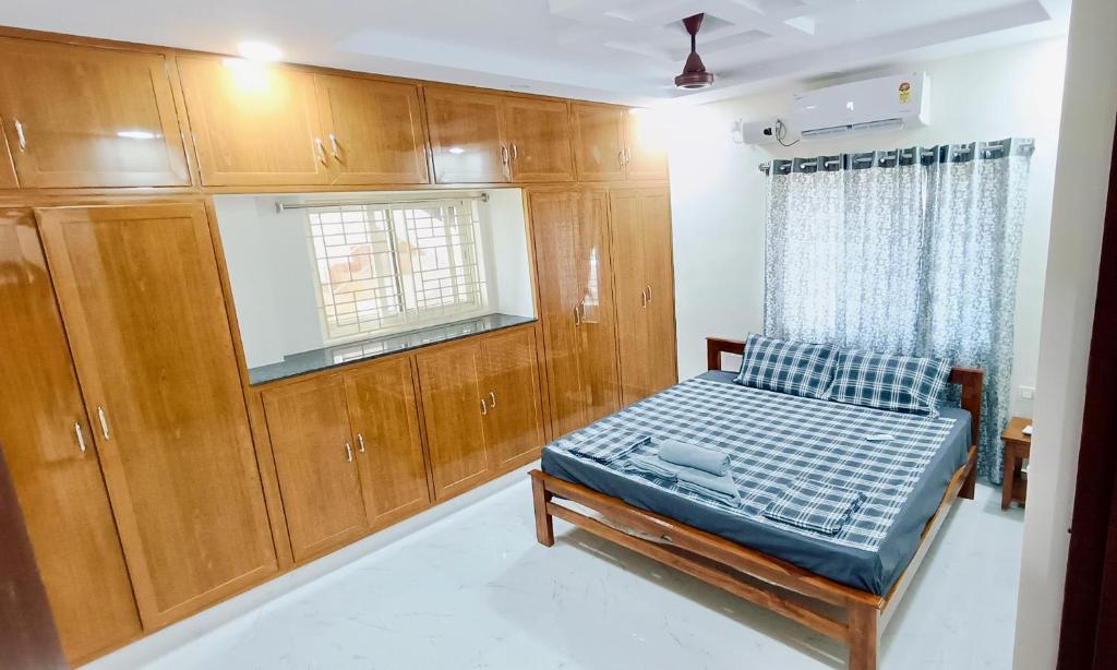 蒂鲁帕蒂TrueLife Homestays - Chinmai Nivas - Modern 2BHK homes for family - Tirumala Mountain View - Best Peaceful Location - Many restaurants nearby - Large hall, AC bedrooms, Modular Kitchen - Fast WiFi - Android TV - 250 Jio Channels的一间带一张床和木制橱柜的小卧室