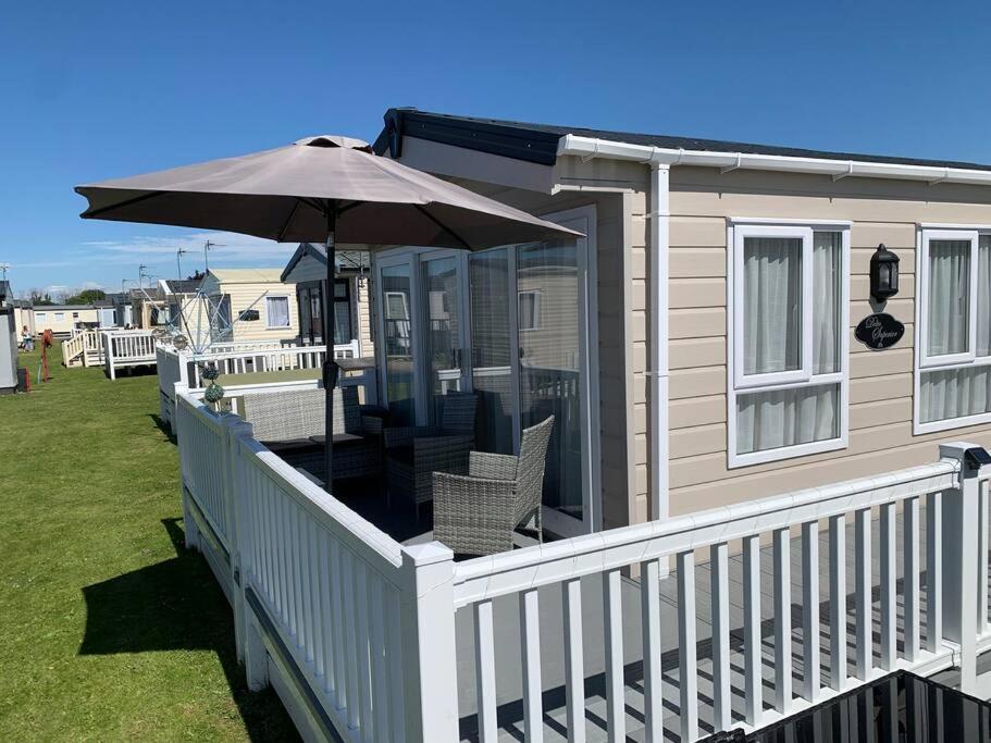 Kinmel Bay6 berth luxury caravan, Lyons Winkups Holiday Park的一个带遮阳伞和椅子的门廊的房子