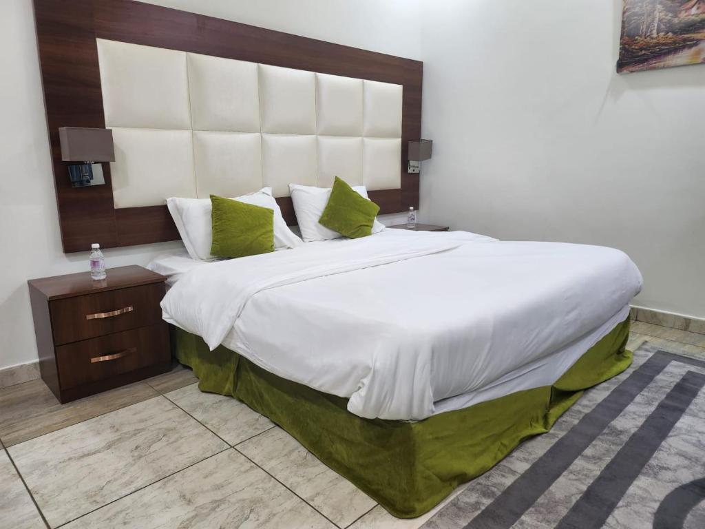 Al Ḩawīyahطرف الطريق的卧室配有带绿色枕头的大型白色床