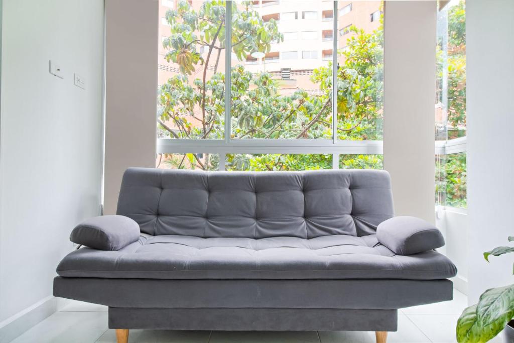 萨瓦内塔Sabaneta Central Nómadas digitales Wi-Fi 401的一张沙发,位于带大窗户的房间里