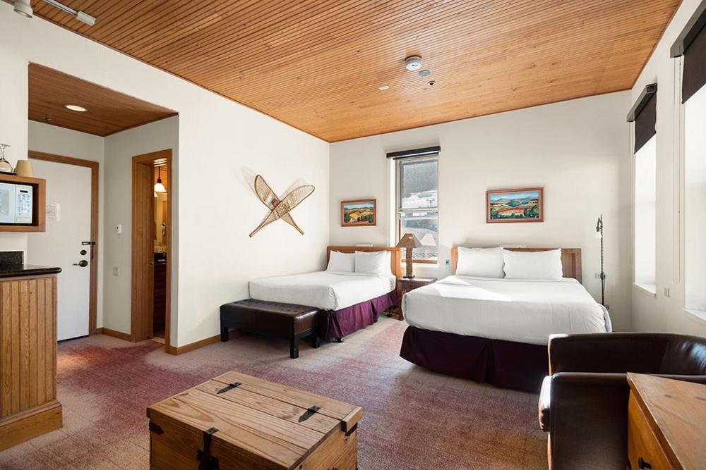 阿斯潘Independence Square Unit 313, Downtown Hotel Room in Aspen with Rooftop Hot Tub的酒店客房设有两张床和一张桌子。
