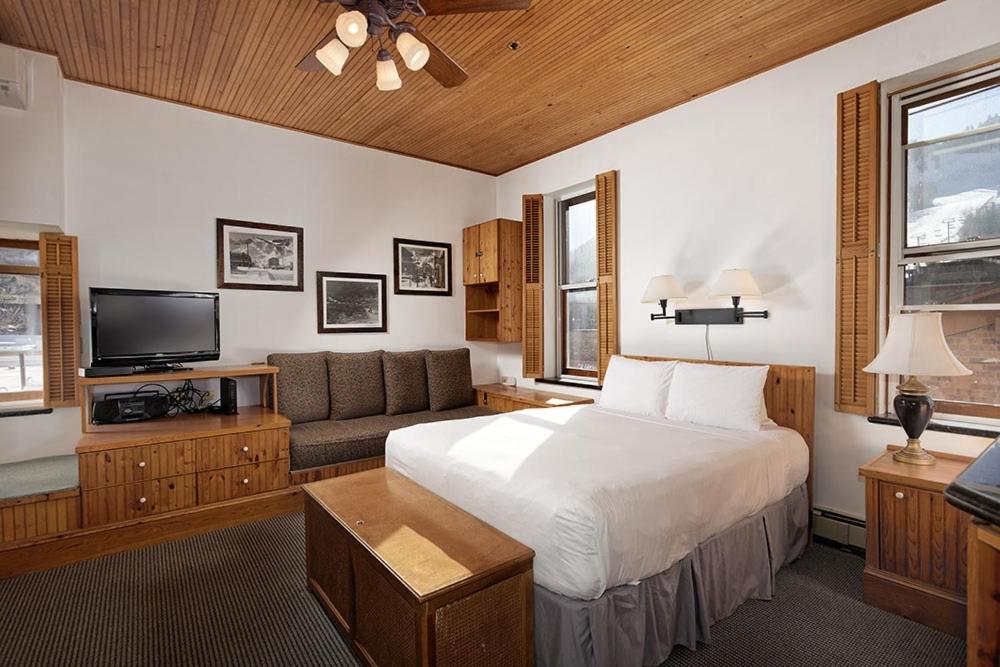 阿斯潘Independence Square 311, Best Location! Hotel Room with Rooftop Hot Tub in Aspen的一间卧室配有一张床、一张沙发和一台电视