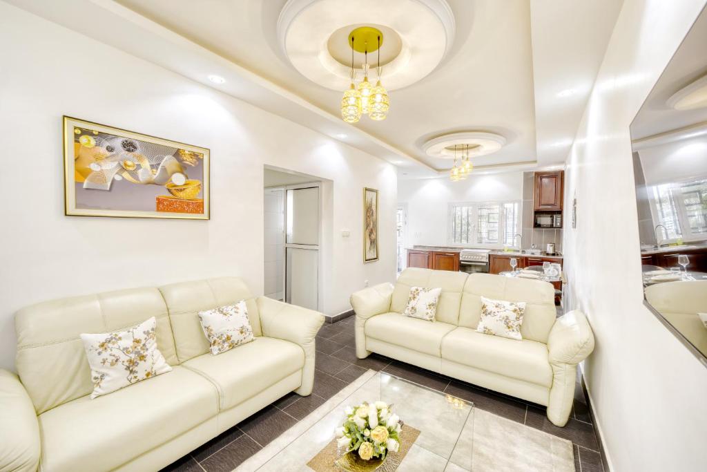 杜阿拉Cosy Home的一间带2张白色沙发的客厅和一间厨房