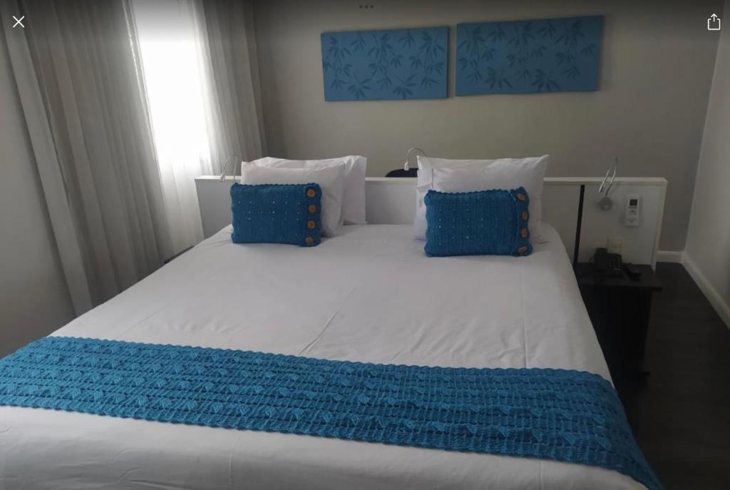 圣保罗Flat Hotel São Paulo, no coração de Moema的一张配有蓝色和白色床单及枕头的大床